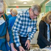 Three alumni looking at past pictures.